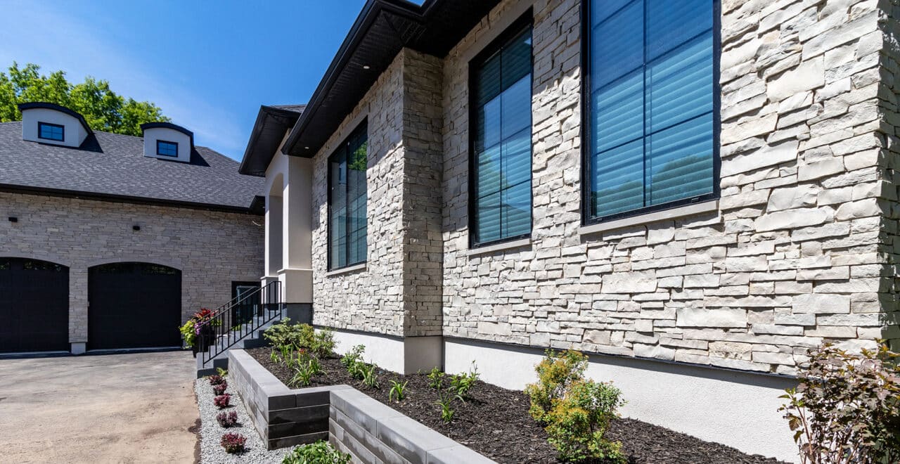 https://buechelstone.com/wp-content/uploads/2019/12/Stone-facade-full-thin-stone-veneers-modern-dream-home-front-wall-stone-exterior-patio-landscaping-HERO-1280x660-8930-e1629134832258.jpg